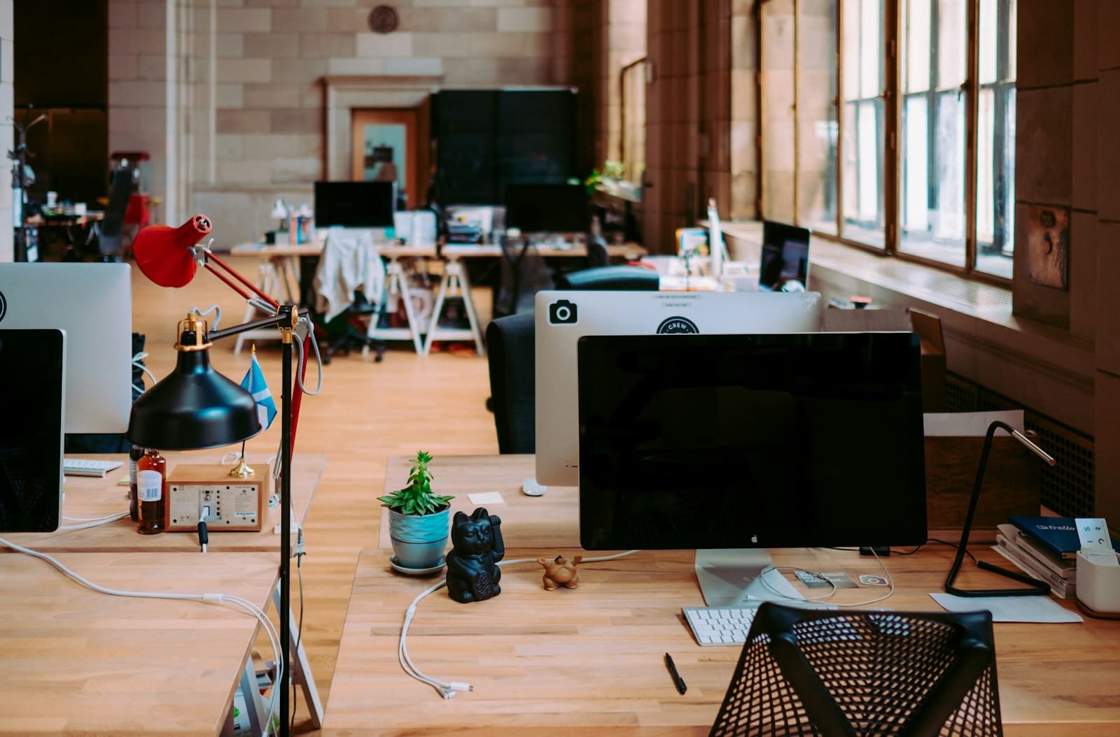 A real, lived-in open office of small desks by tall windows, the everyday workplace of a small IT shop